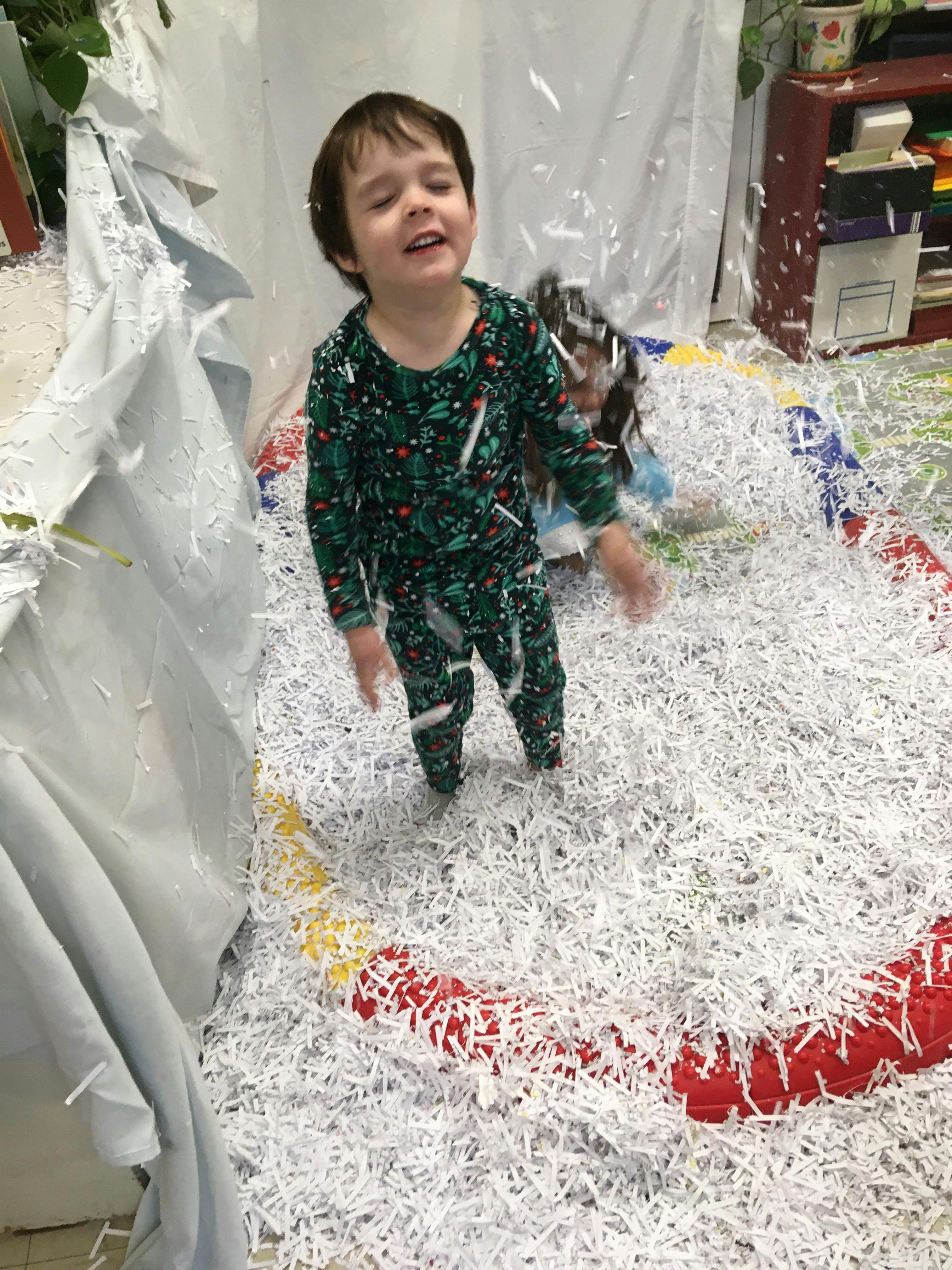 Child standing in a pile of shredded paper