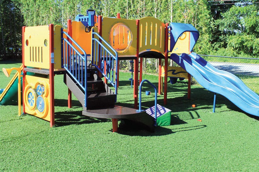 Playground structure with slides and stairs on green turf