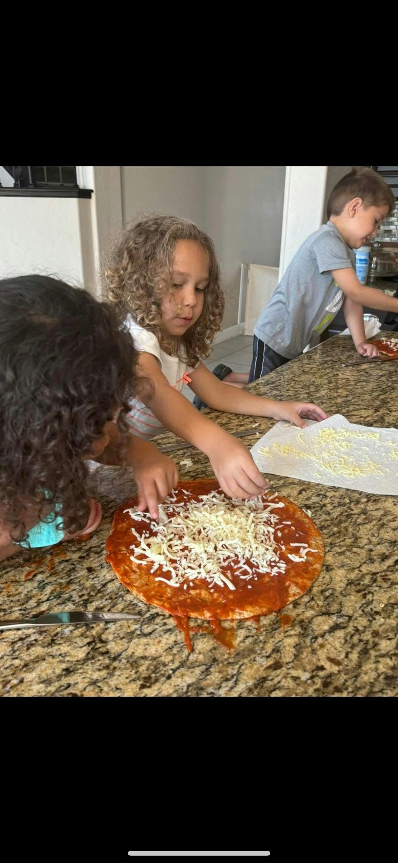 Children making pizza on a kitchen counter