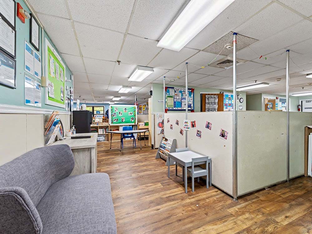 Classroom with light blue walls, wood flooring, and children's tables