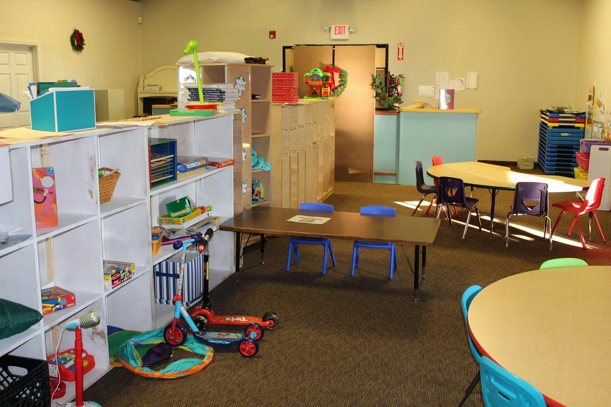 Classroom with tables, chairs, and shelves with toys
