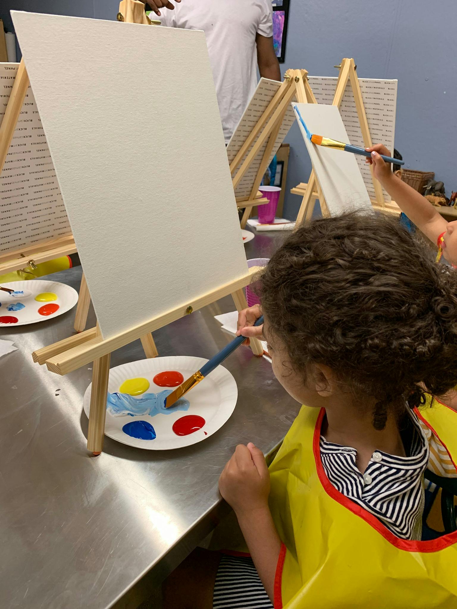 Child painting on a canvas with a brush and palette