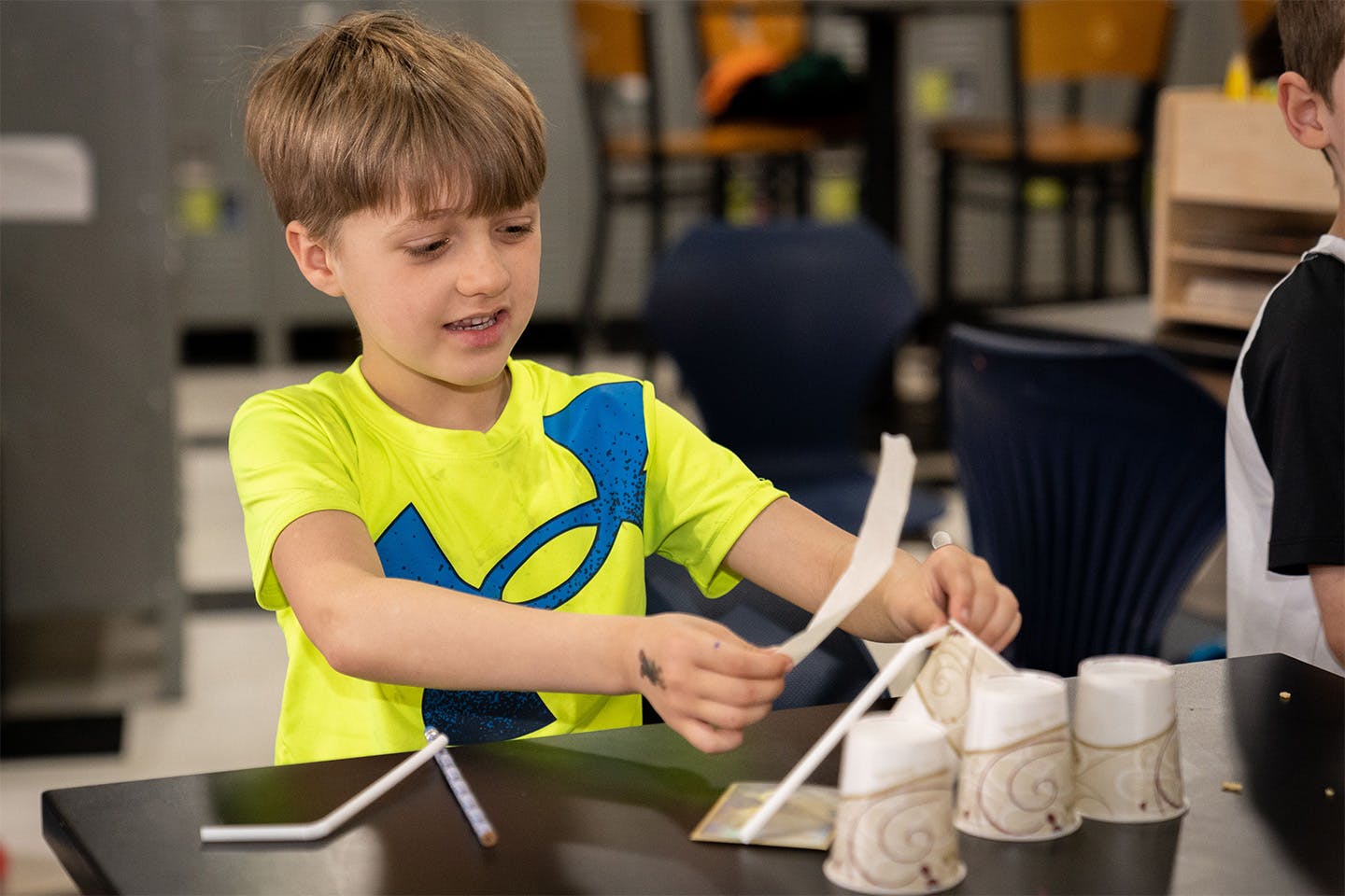 Child building a structure with paper and cups