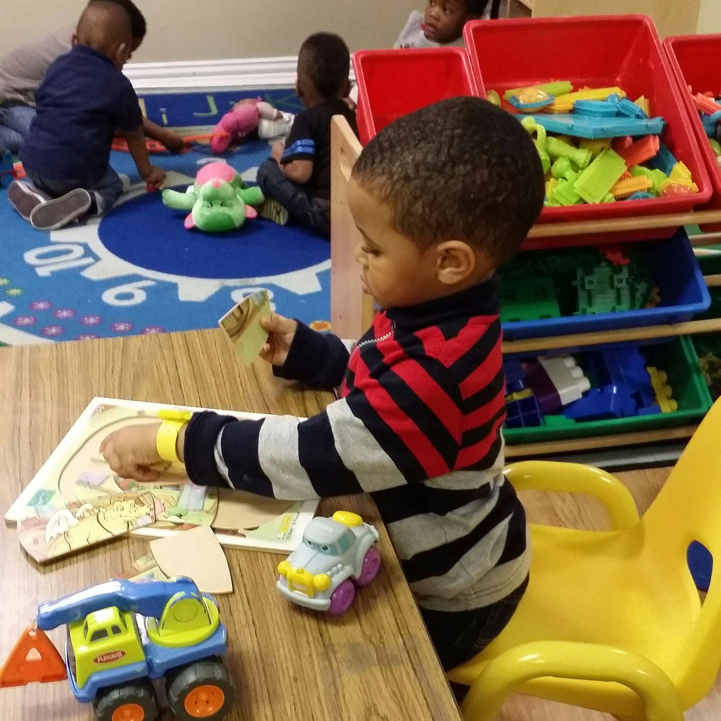 Child playing with a puzzle at a table in a classroom