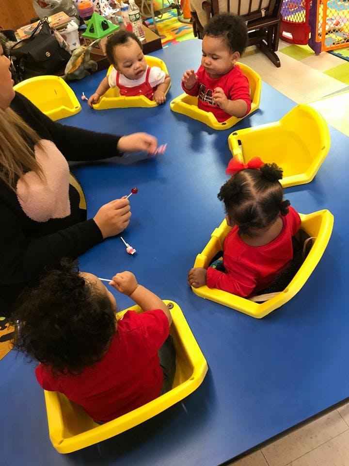 Adult and multiple children sitting at a table with lollipops