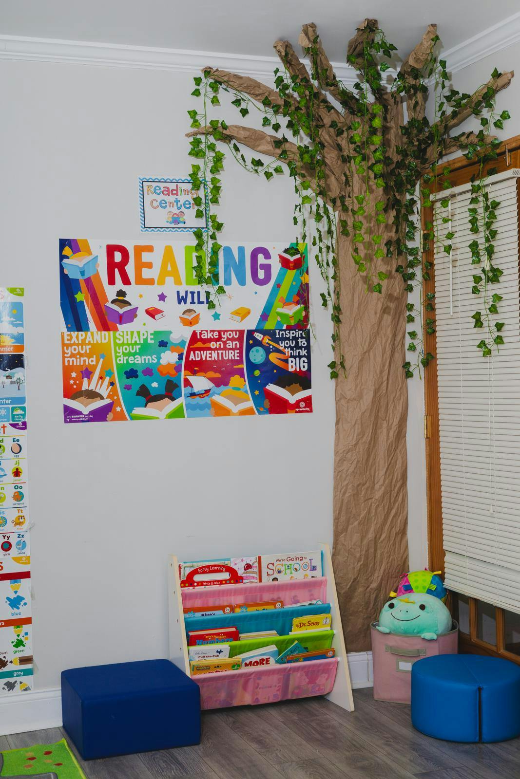 Reading corner with a colorful poster, a tree decoration, and a book display