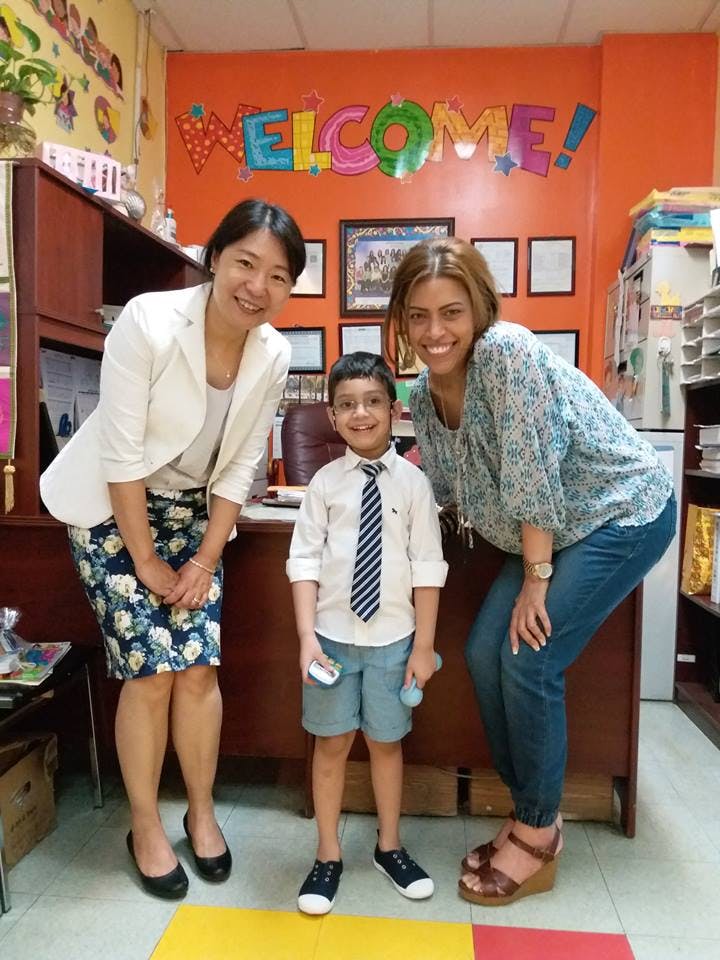 Two people and a child standing in front of a "WELCOME!" sign
