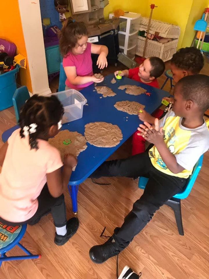 Children playing with kinetic sand at a blue table