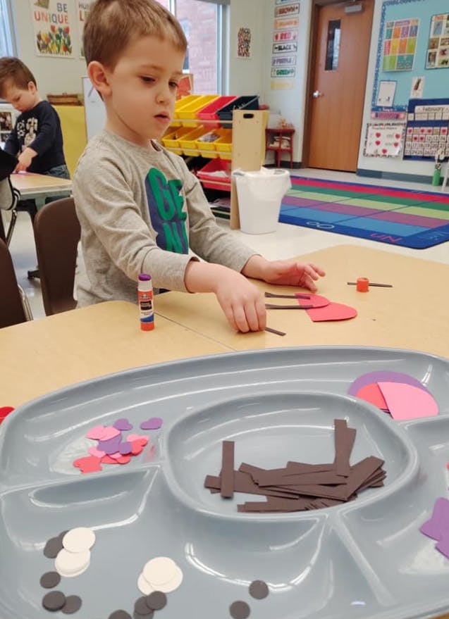 Child doing a craft at a table in a classroom