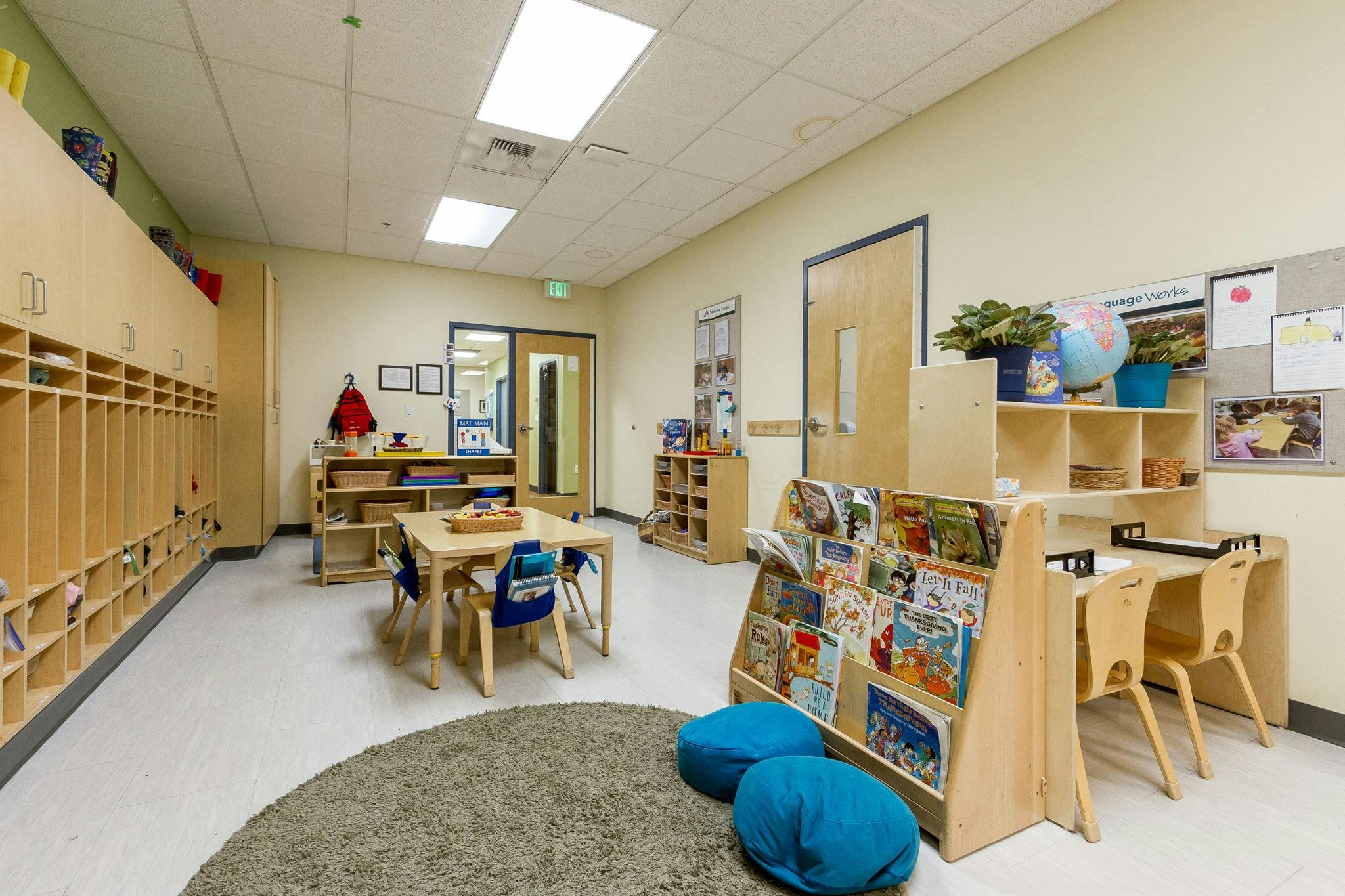 Empty classroom with small tables, chairs, and cubbies
