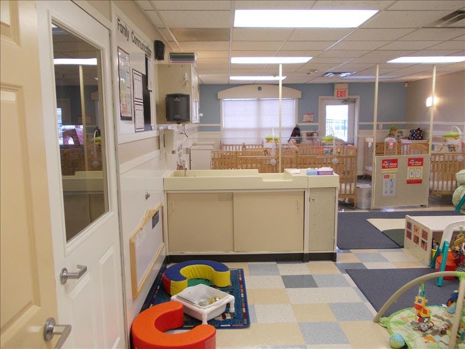 A changing station with cribs and play mats in a childcare room