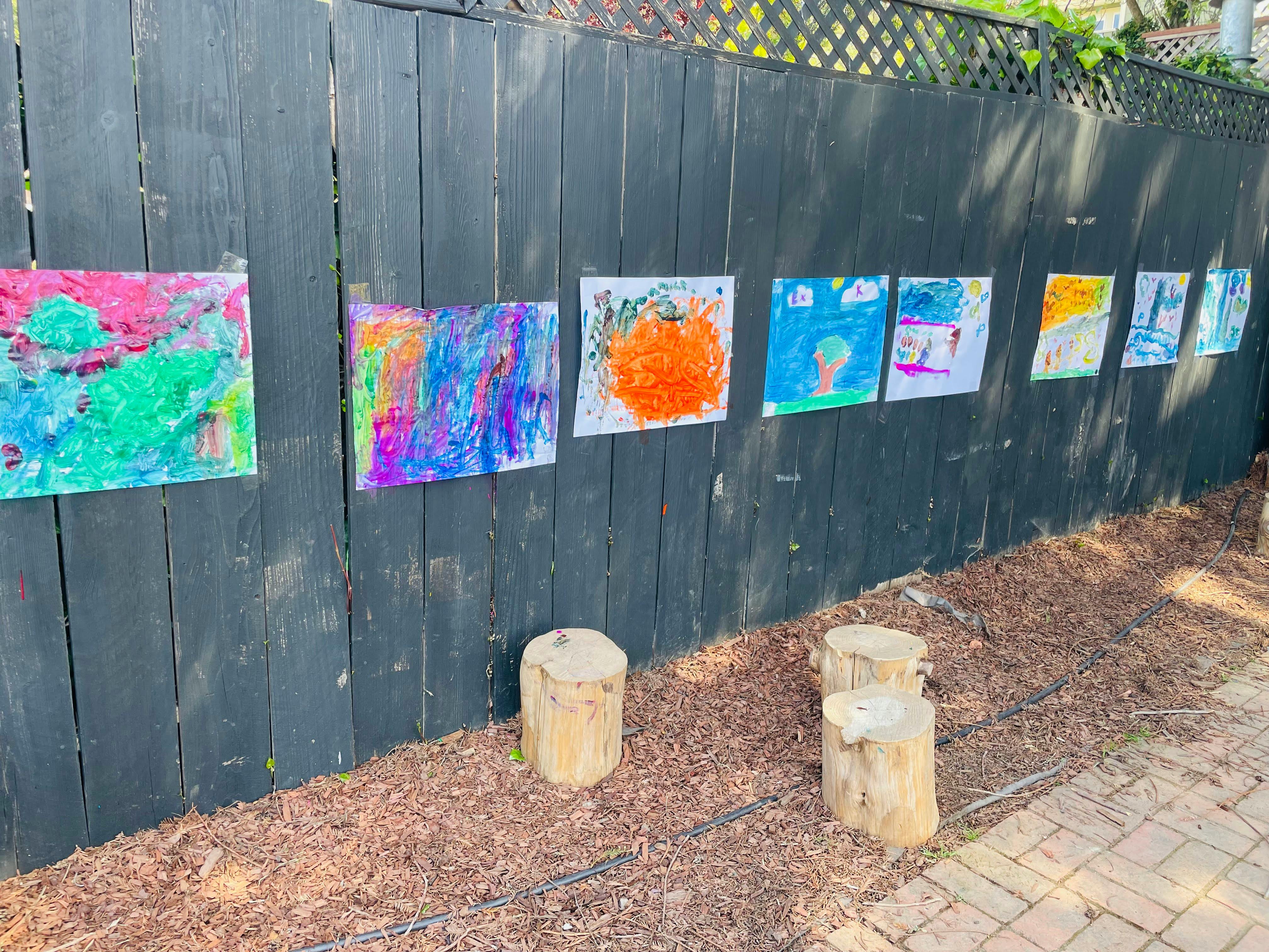 Children's artwork displayed on a fence