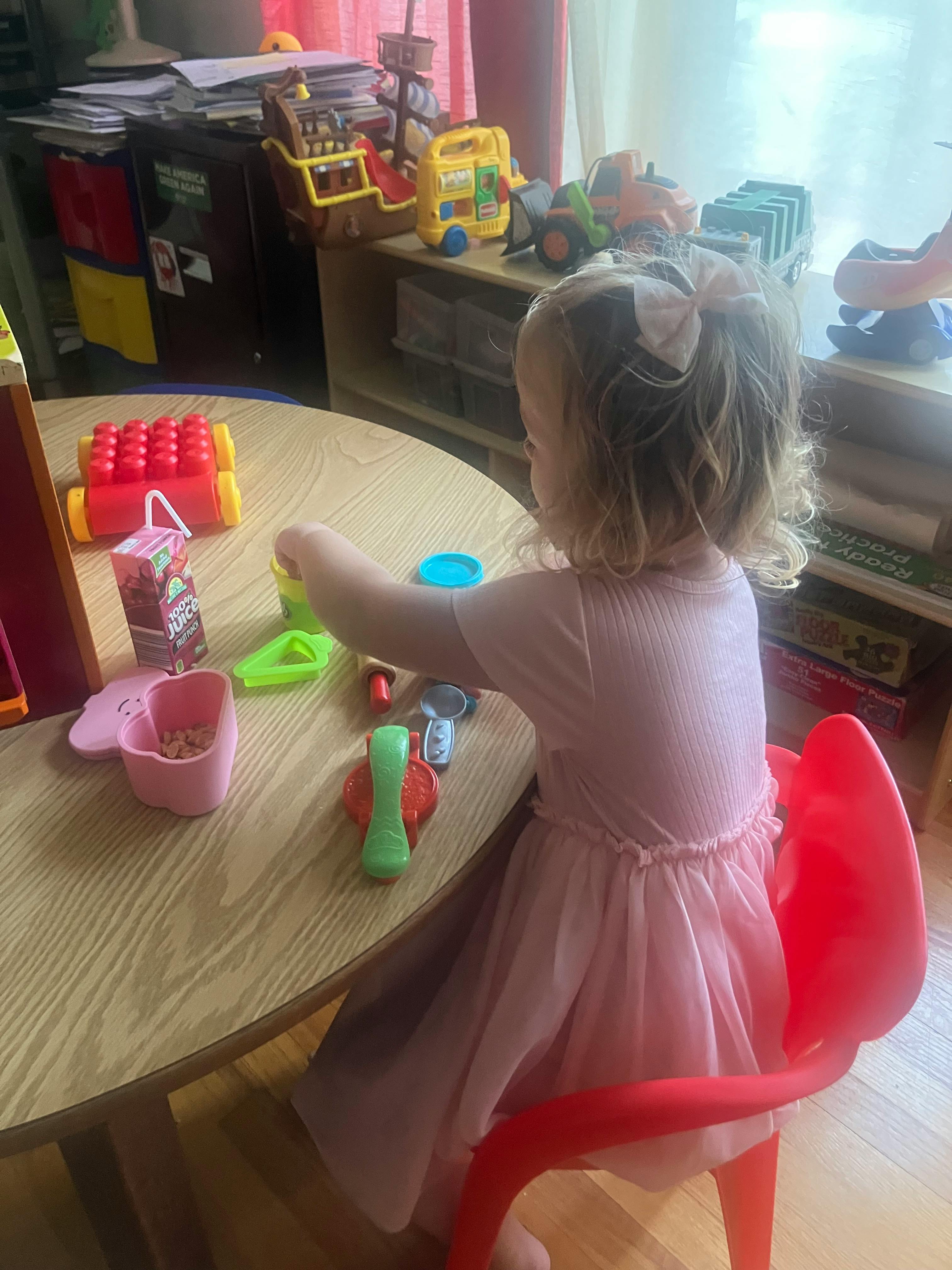 Child sitting at a wooden table playing with plastic toys