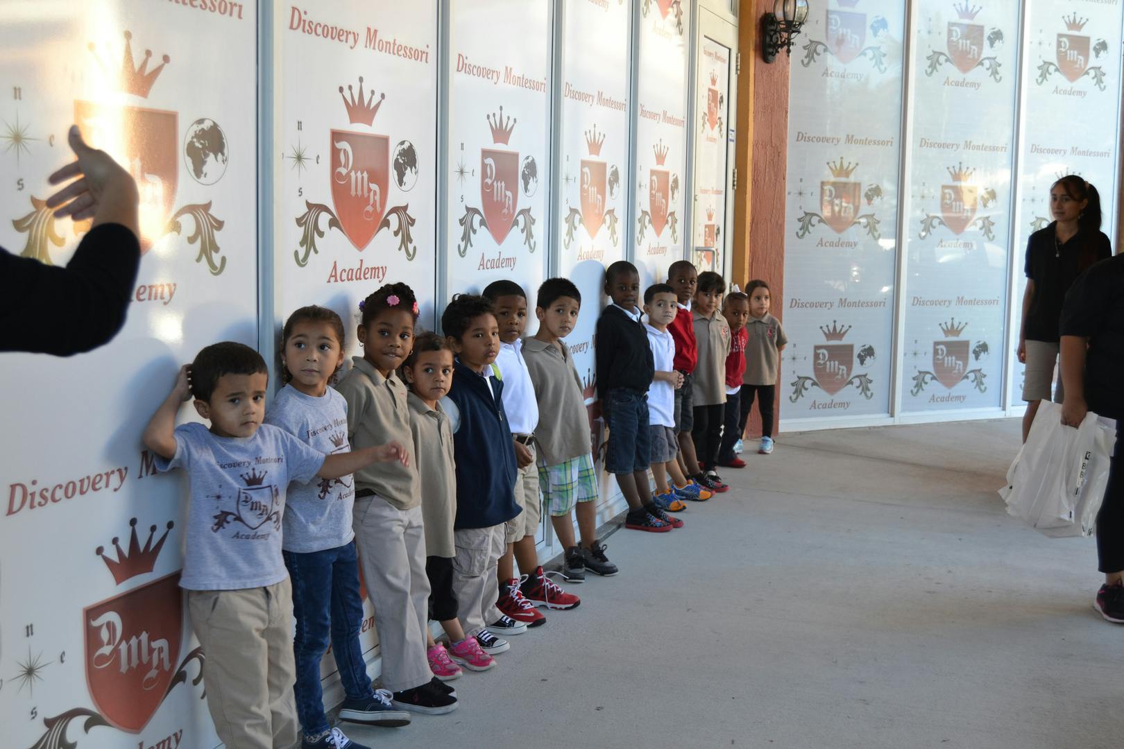 Children standing in a line against a wall with crests