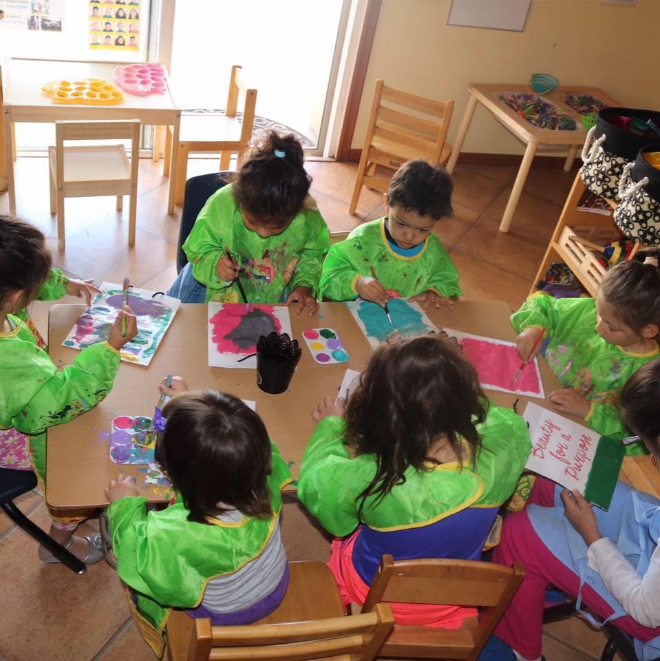 Children painting at a table in a classroom