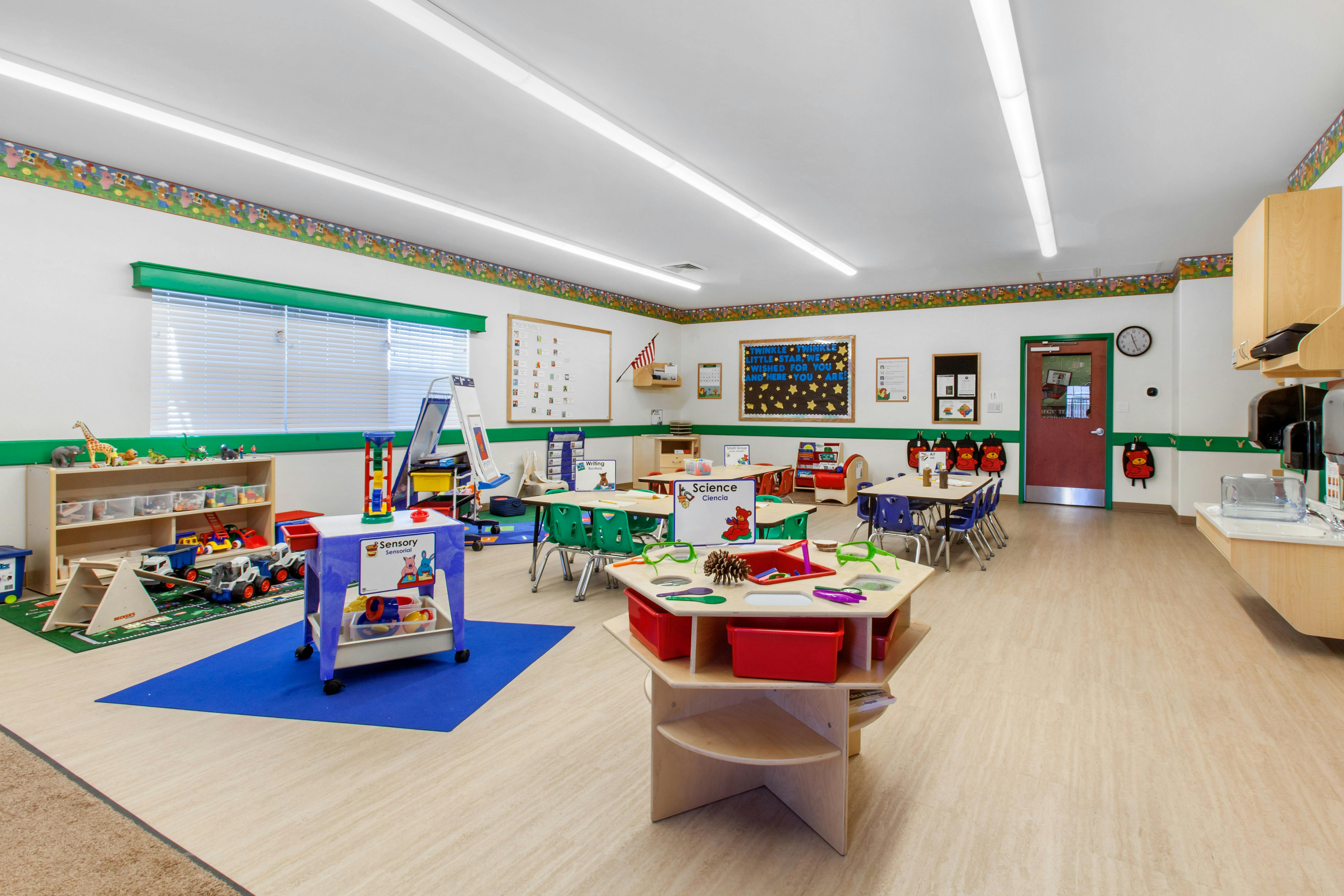 A colorful classroom with tables, chairs, toys, and learning stations