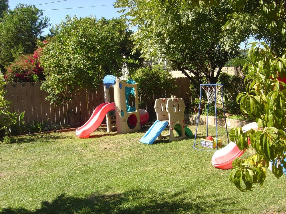 Playground with slides and basketball hoop in a grassy yard
