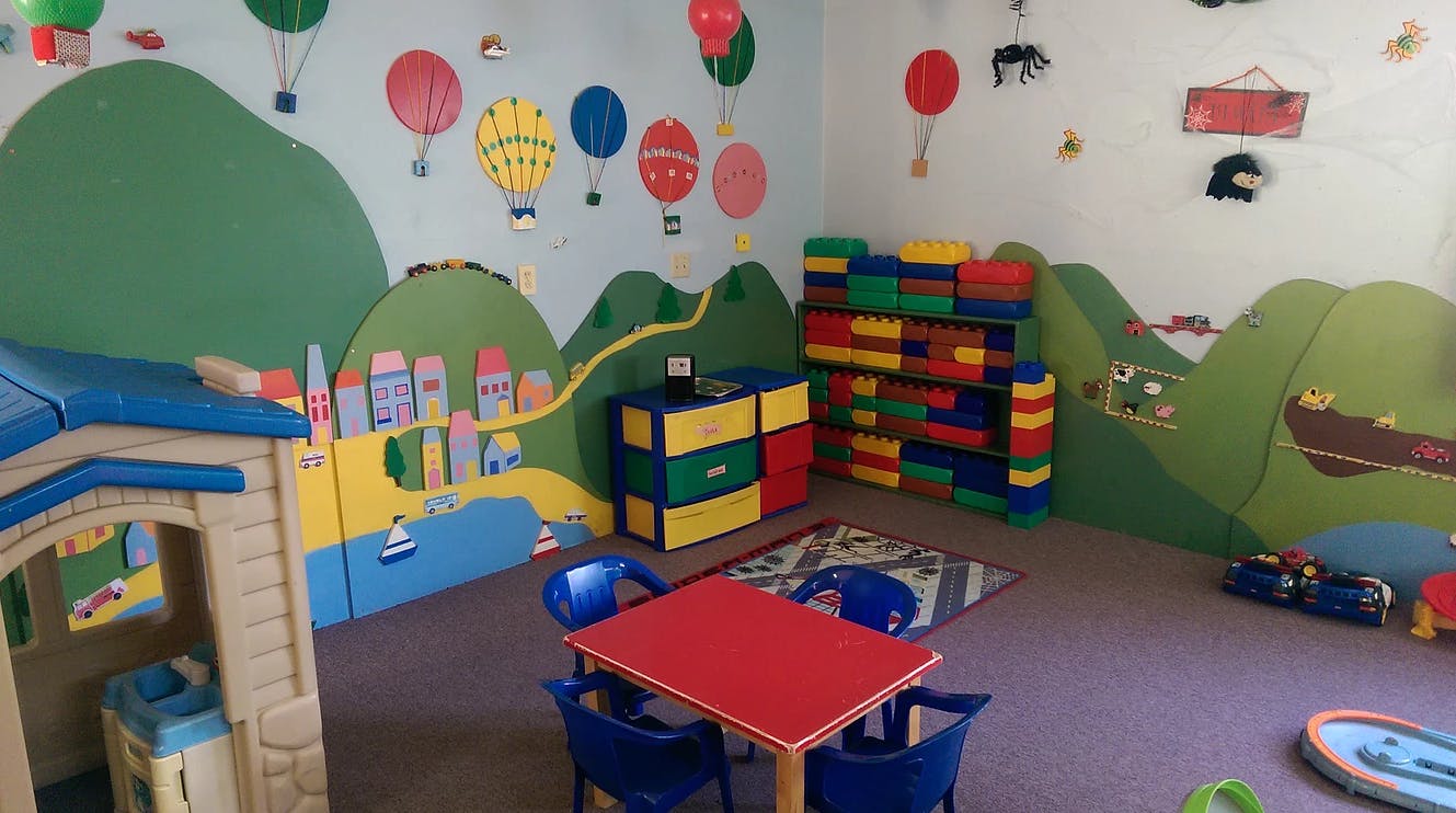 Playroom with colorful wall murals, toy storage, and small table and chairs