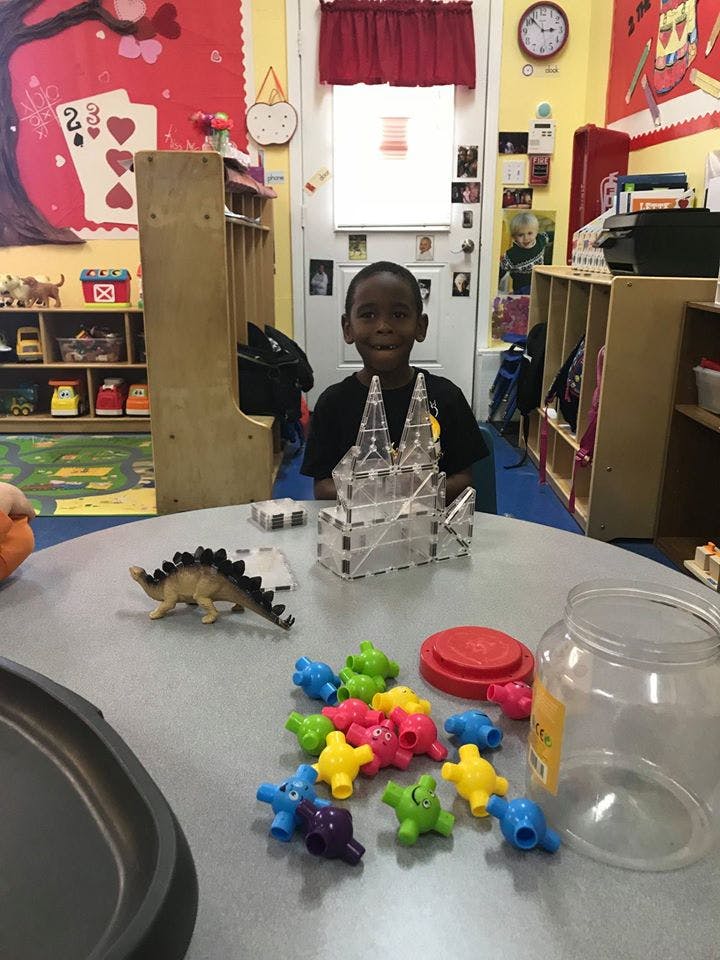 Child at a table with toys, including a clear plastic castle and colorful plastic shapes