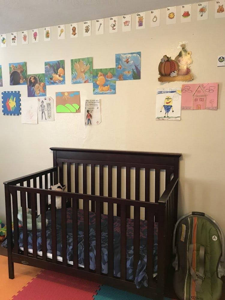 Dark wood crib in a room with children's drawings on the wall