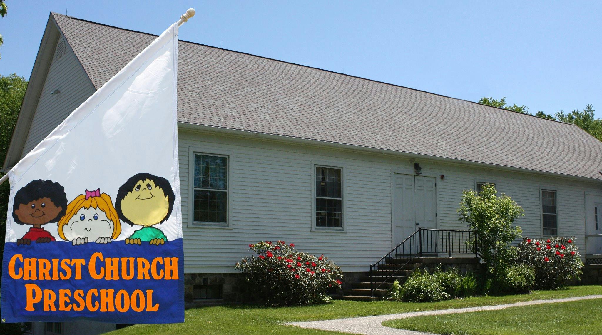 Flag with cartoon children and "Christ Church Preschool" text in front of a building