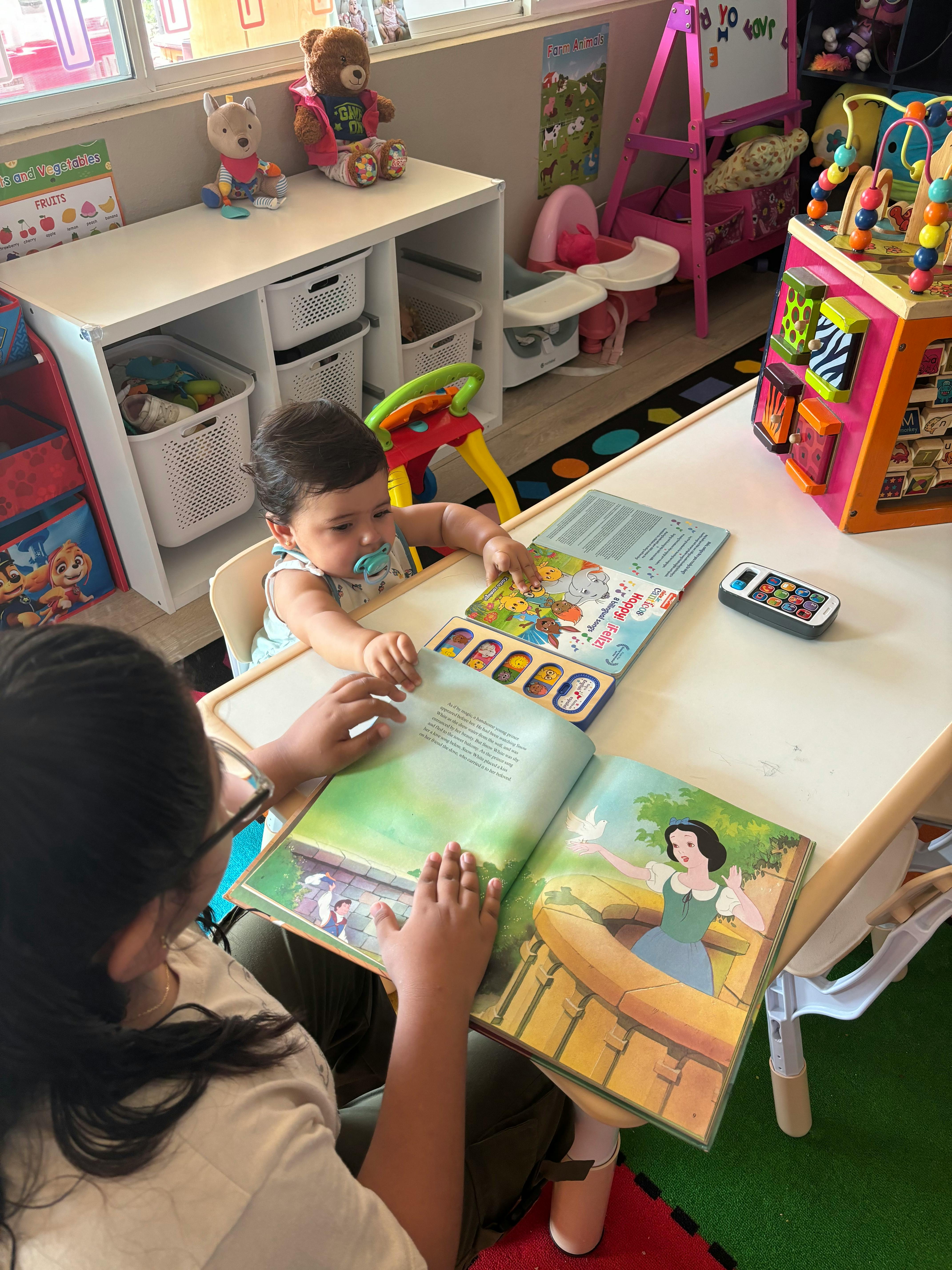 Person and child reading a book together at a table