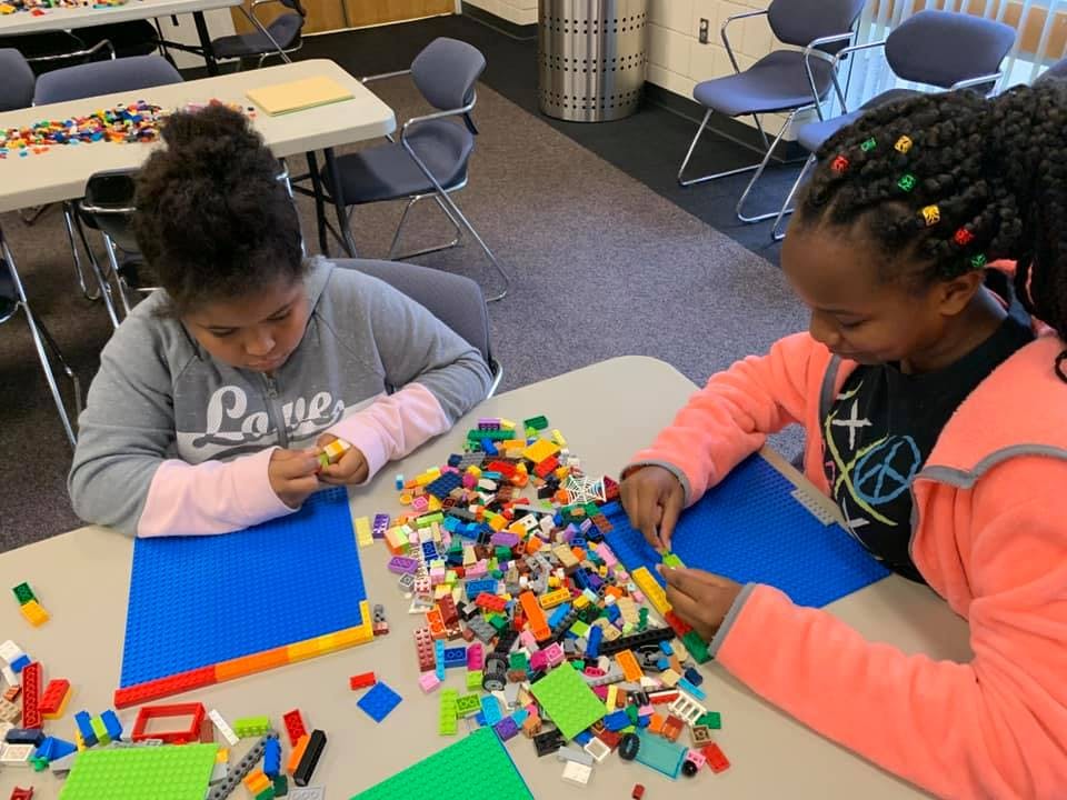 Two children building with colorful interlocking toy bricks at a table