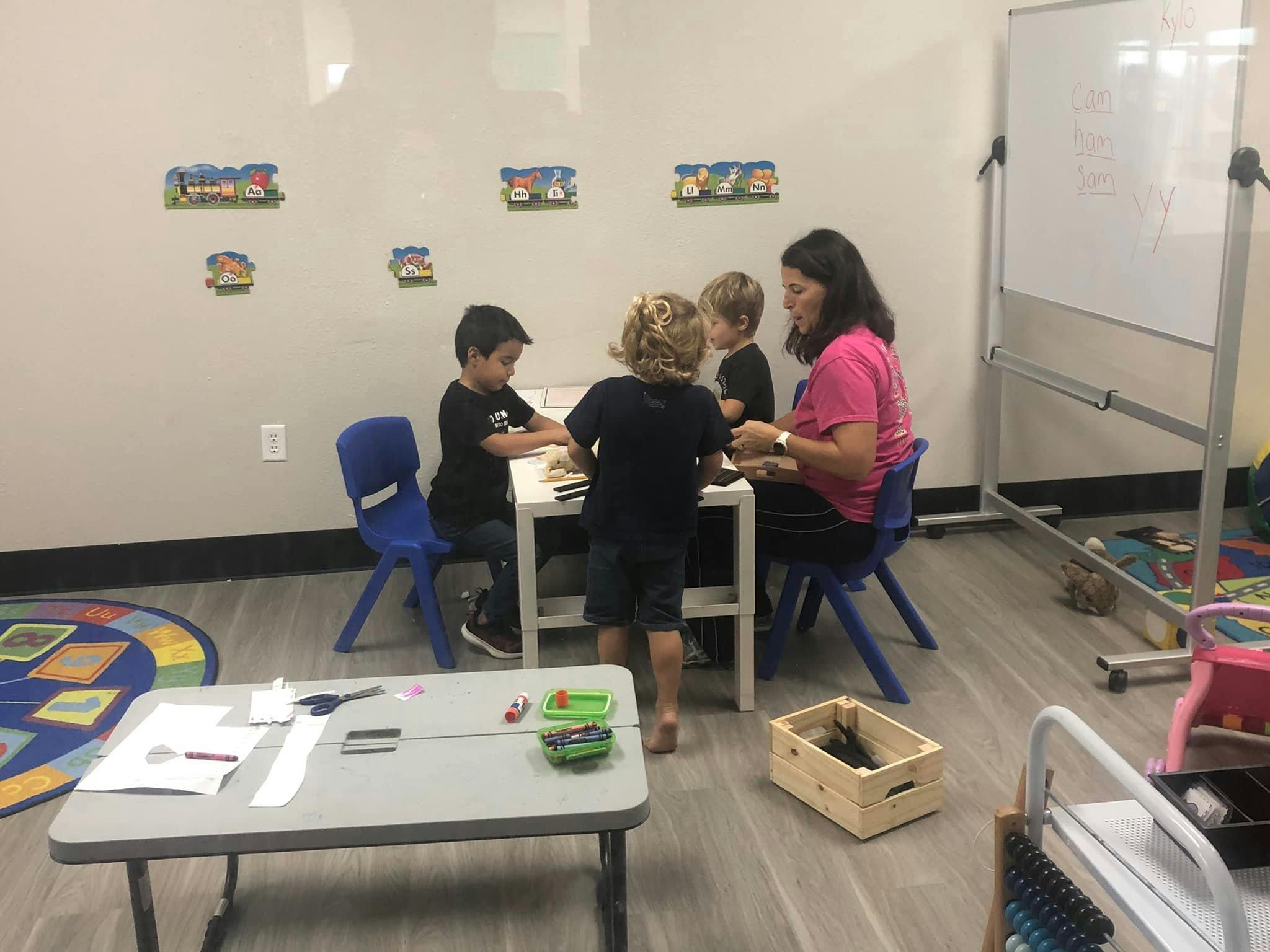 Adult and three children at a table in a classroom
