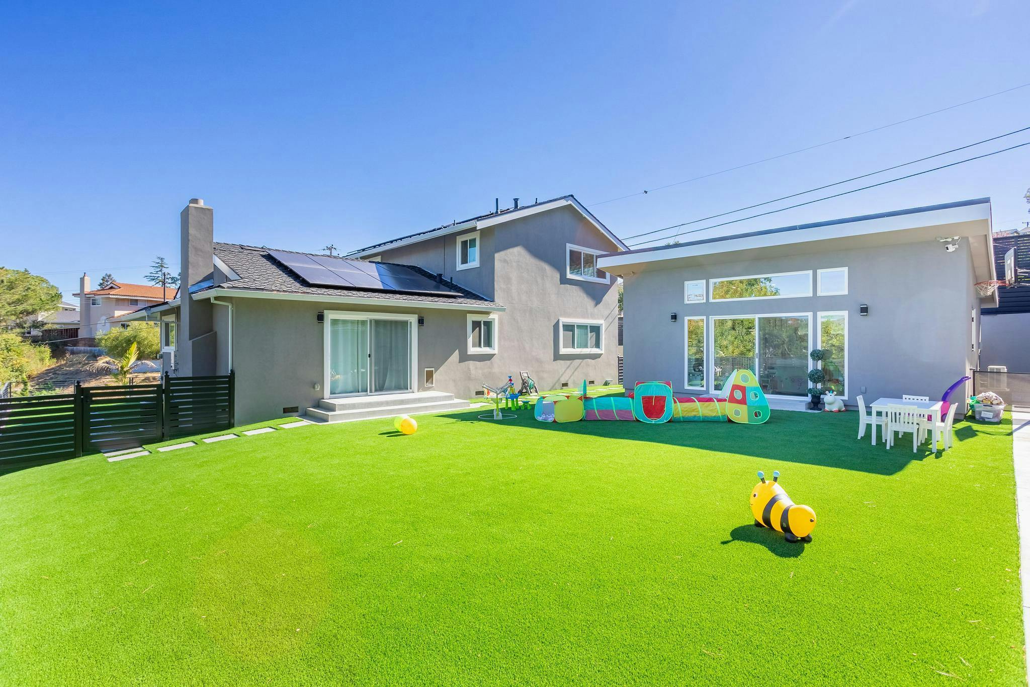 Backyard with green lawn and house with solar panels