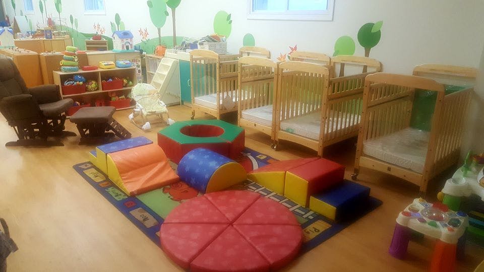 Playroom with soft play equipment, cribs, and a rocking chair