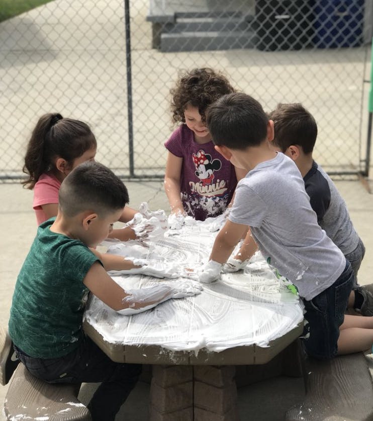 Children playing with shaving cream on a picnic table