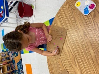 Child painting on a piece of cardboard at a table