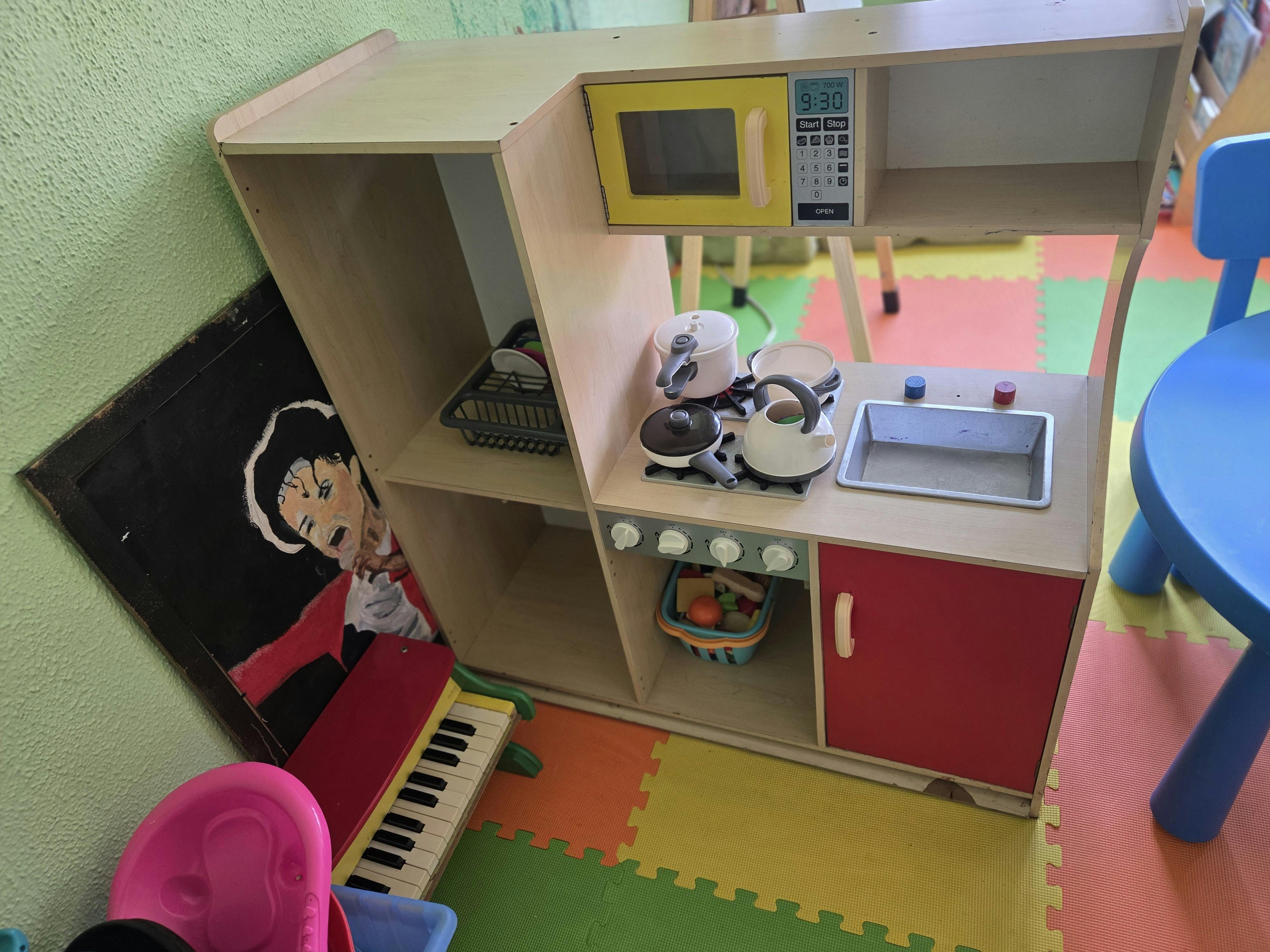 Child's play kitchen with a microwave, sink, and stove