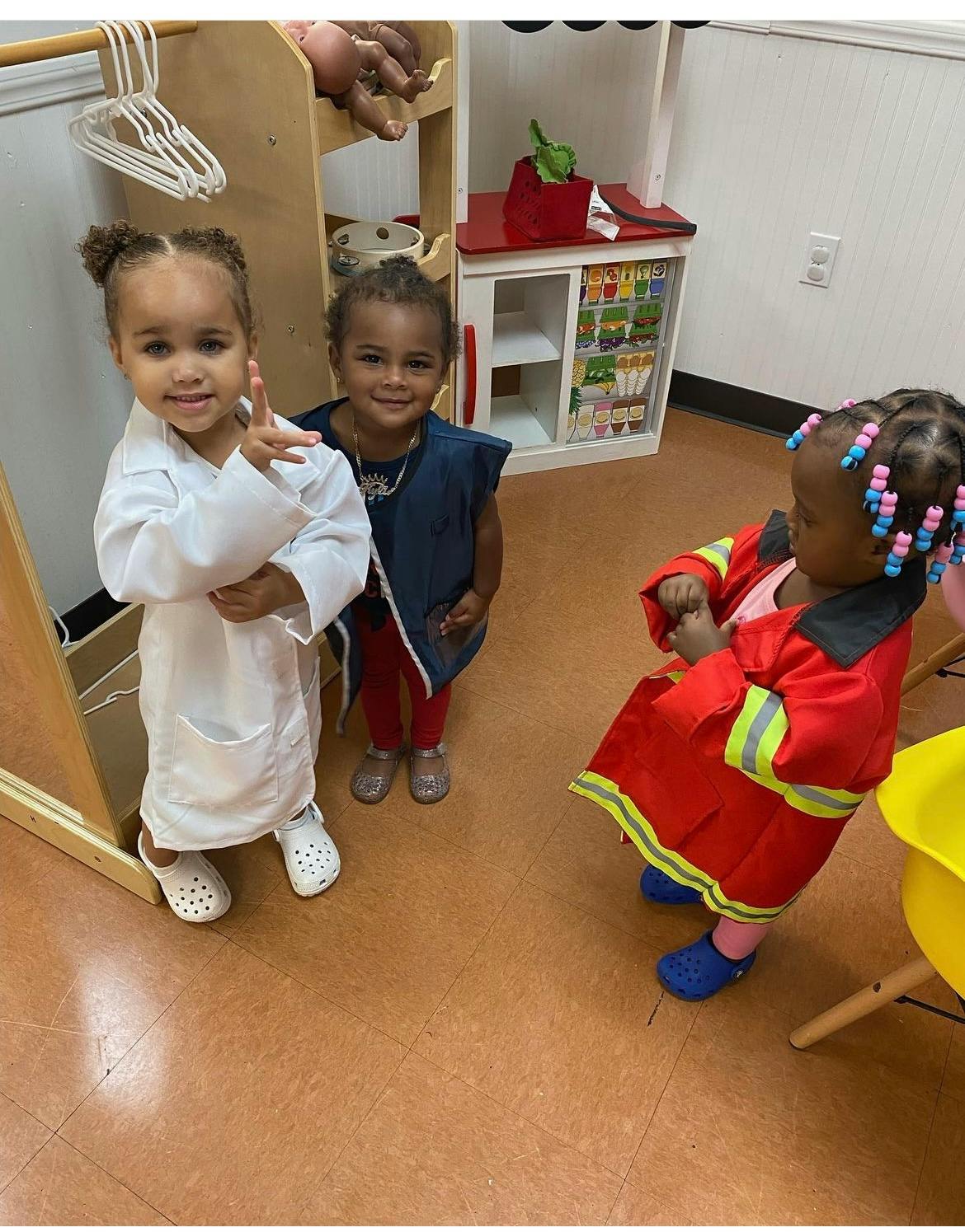Three children playing dress-up in a classroom