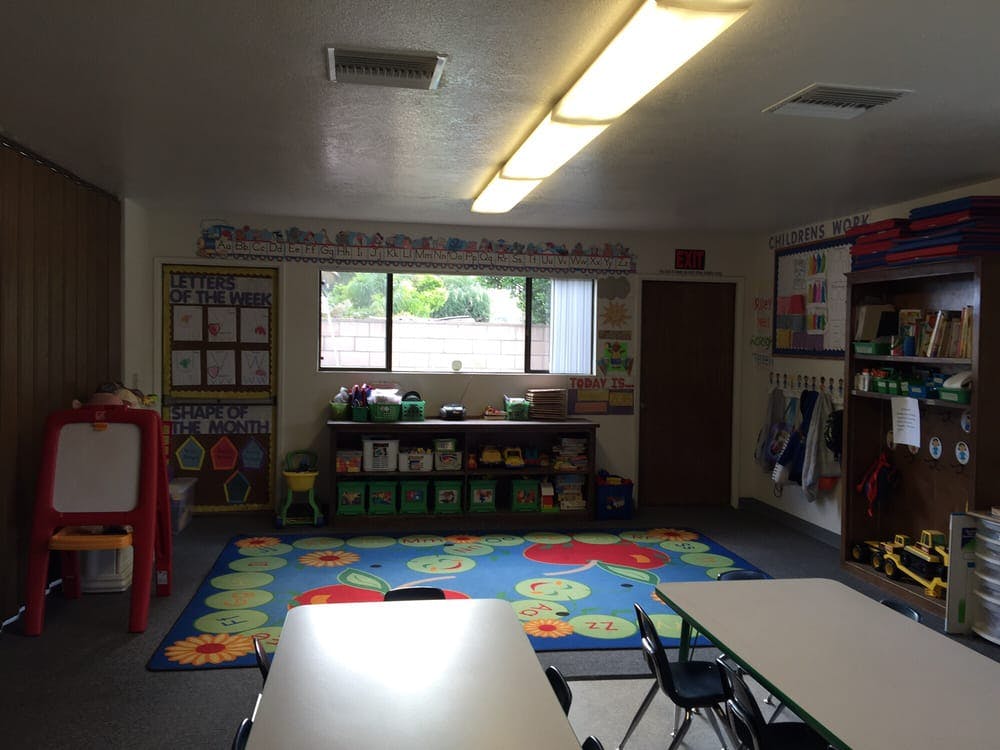 Classroom with tables, chairs, and a colorful rug
