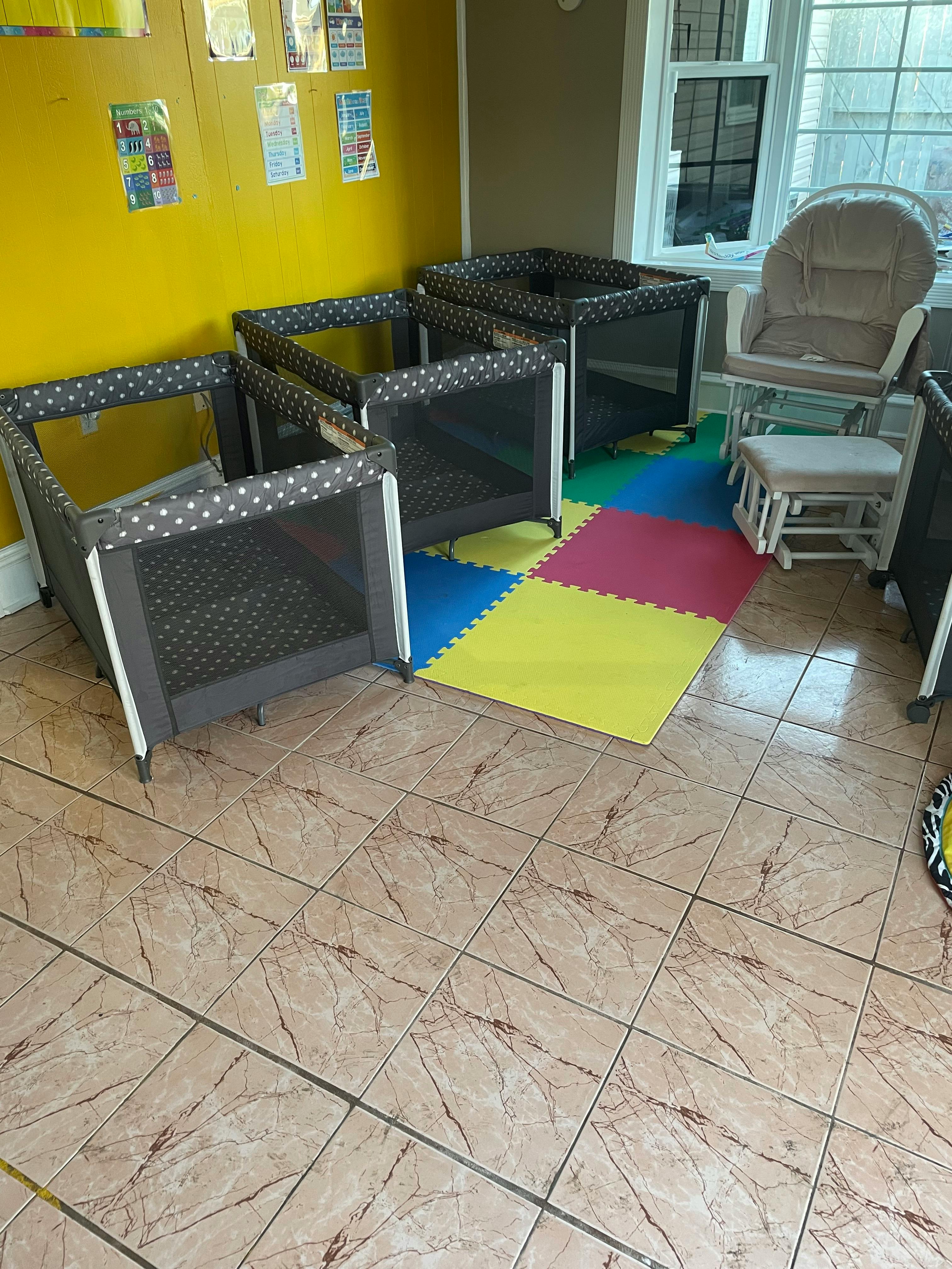 Multiple playpens on a colorful mat in a room
