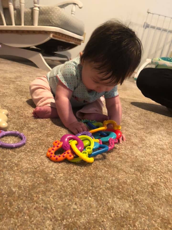 Child on carpet playing with colorful plastic toy