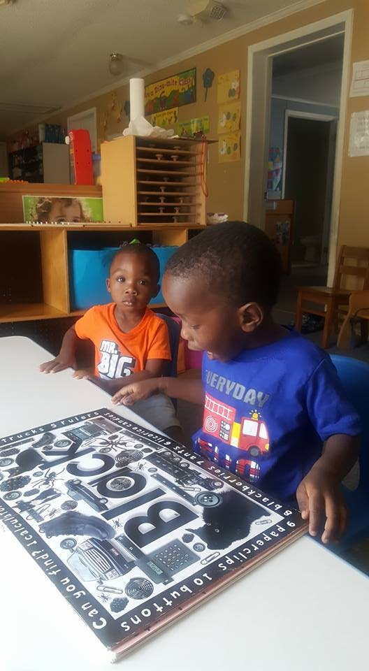 Two children looking at a book at a table in a classroom