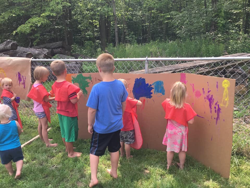 Children painting on cardboard outdoors