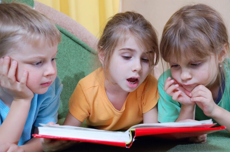 Three children reading a book together