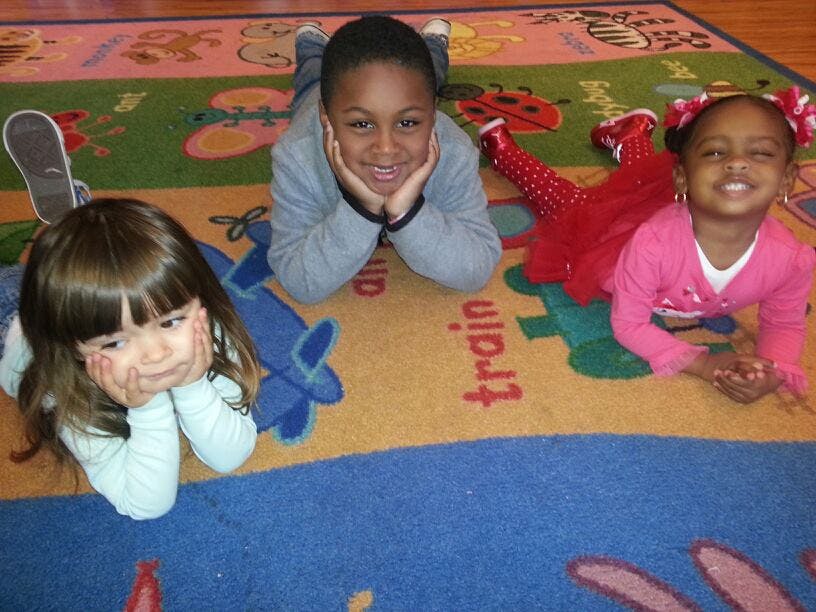 Three children lying on a colorful rug