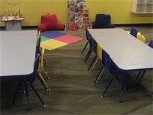 Classroom with two tables and chairs, colorful mat on floor