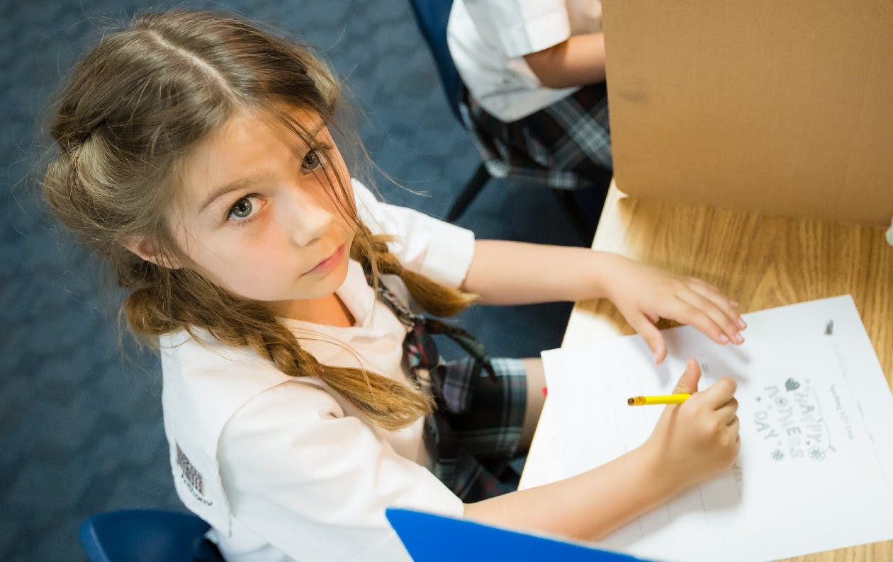Child writing on paper with a pencil