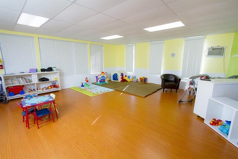 Playroom with small table and chairs, shelves, and play mats