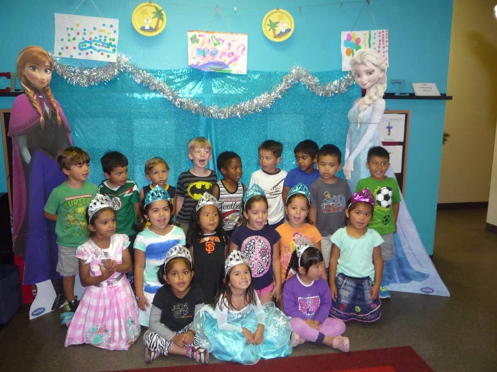 Group of children wearing crowns and costumes in front of a blue background
