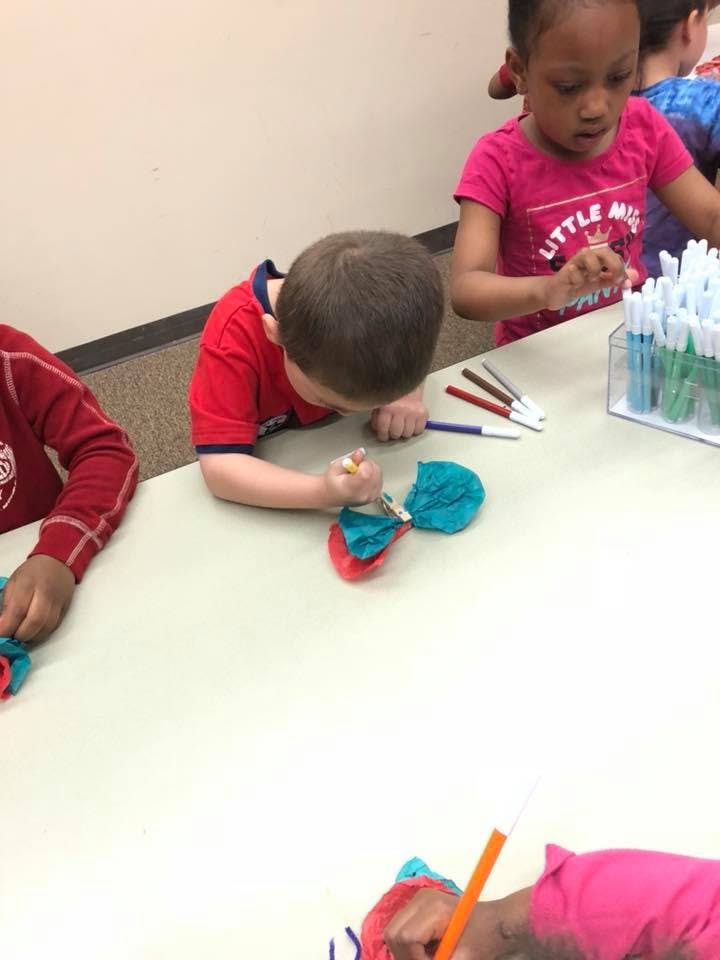 Child coloring a craft at a table with other children