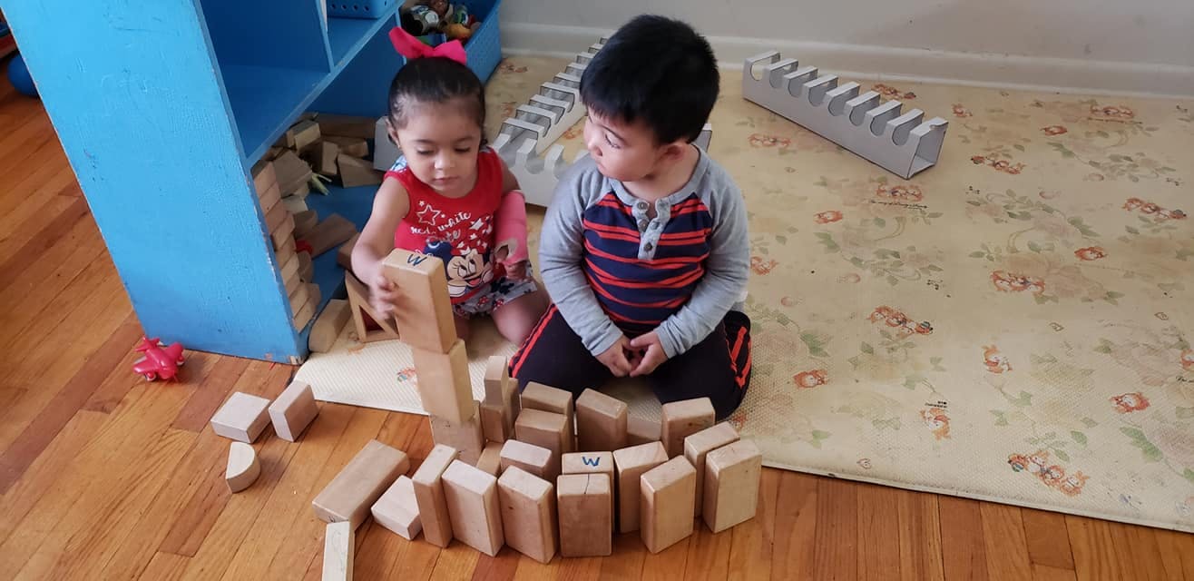 Two children playing with wooden blocks on the floor