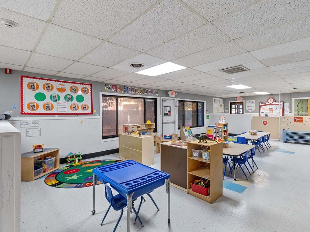 Classroom with small tables, chairs, and play areas