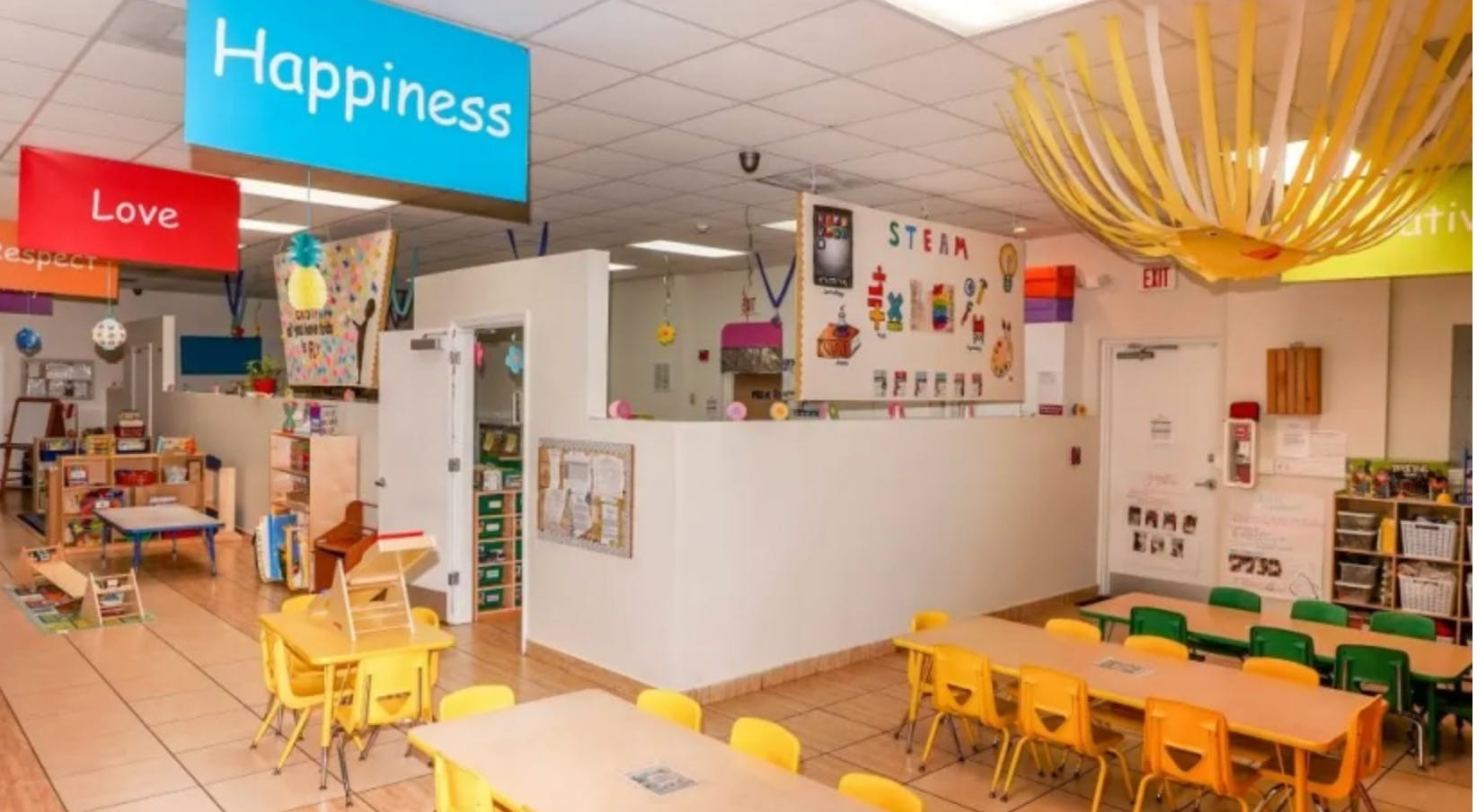 Classroom with small tables and chairs, signs reading Happiness and Love