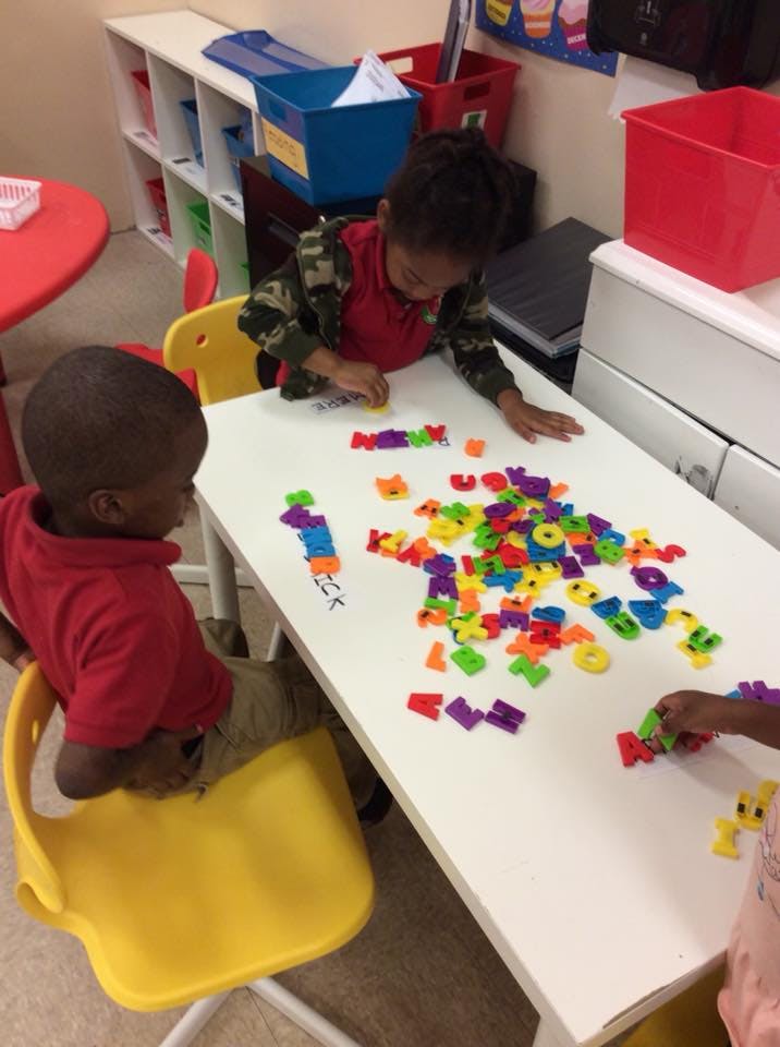 Two children playing with colorful letter magnets on a white table